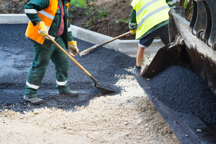 Workers making asphalt with shovels at road construction